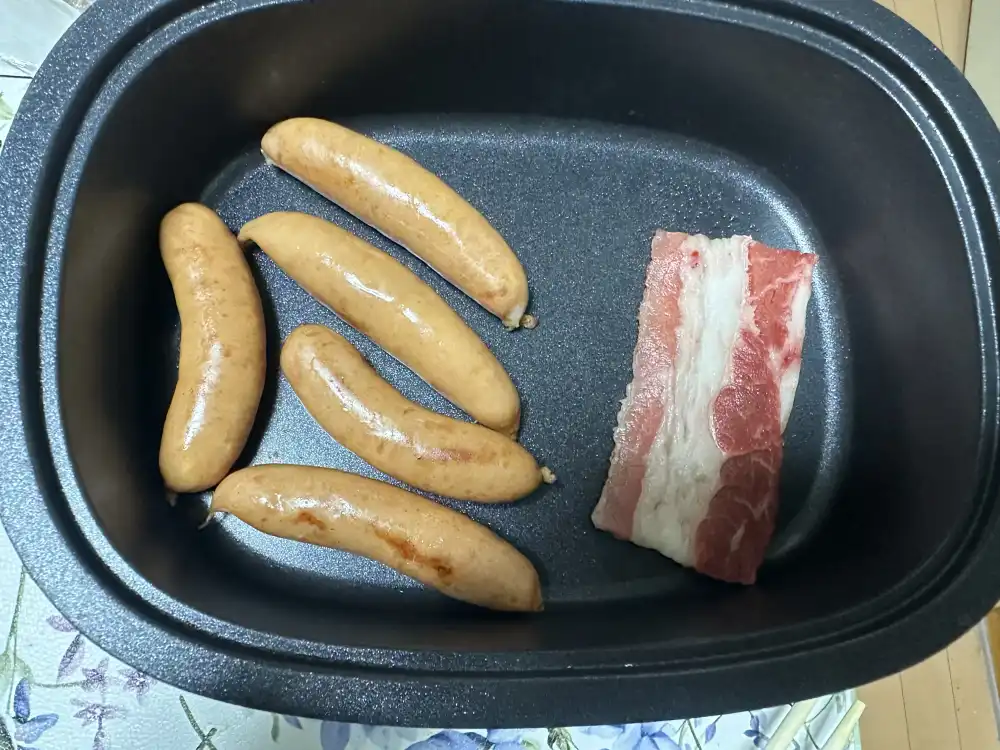 一人焼肉でソーセージと豚バラを焼いている